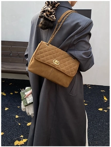 Détail d'un sac cabas marron en daim matelassé avec fermoir doré et chaîne en cuir