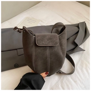 Detailed view of dark brown suede bucket bag featuring high-contrast white stitching design