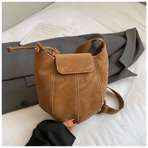 Detail view of brown suede bucket bag featuring contrast white stitching and drawstring