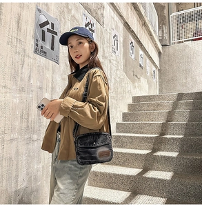 Gros plan sur un sac bandoulière en denim noir avec poche à bouton-pression et style urbain