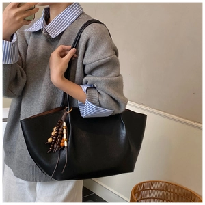 Detail of black tote bag with colorful beaded tassel pendant and matte leather finish