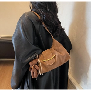 Detail of caramel pleated shoulder bag with gold crescent buckle and plush bear charm