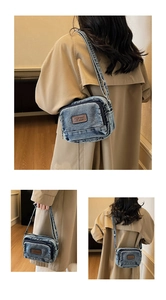 Détail du sac bandoulière en denim bleu délavé avec écusson en cuir et poche zippée
