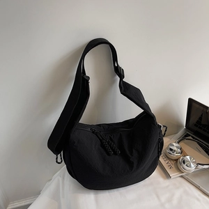 Dettaglio della borsa a mezzaluna in nylon nero con doppie cerniere e tracolla larga