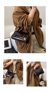 Dettaglio borsa in pelle marrone lucida con hardware in bronzo e tracolla regolabile