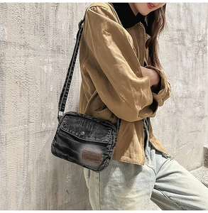 Gros plan sur un sac bandoulière en jean noir délavé avec étiquette en cuir brun
