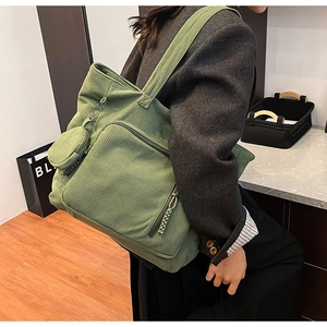 Dettaglio della borsa tote in velluto a coste verde con tasca a zip e mini borsellino tondo