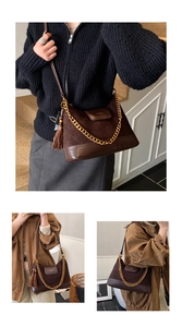Detail of dark brown suede shoulder bag featuring a gold chain strap and tassel