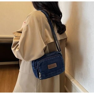 Vue détaillée d'un sac bandoulière en jean vintage avec zips multiples et écusson logo