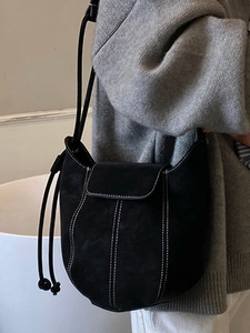 Minimalist black frosted suede bucket bag with white contrast stitching for winter 2025
