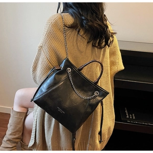 Dettaglio della borsa tote in pelle nera con catene argentate e logo del marchio stampato
