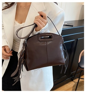 Détail du sac en cuir marron foncé avec poignée ovale et franges latérales élégantes