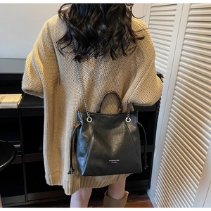 Dettaglio borsa tote in pelle nera con catena argentata e manico marrone stampato