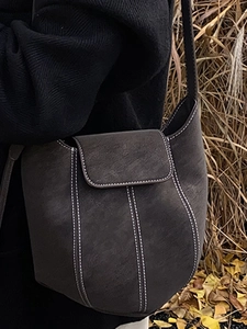Minimalist grey suede bucket bag with contrast white stitching and leather strap