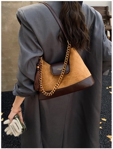 Close-up of retro brown suede patchwork shoulder bag with gold chain and fringe