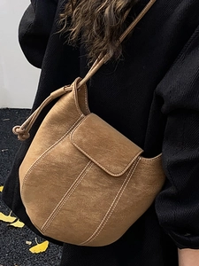 Brown frosted suede bucket bag with white contrast stitching and knotted shoulder strap