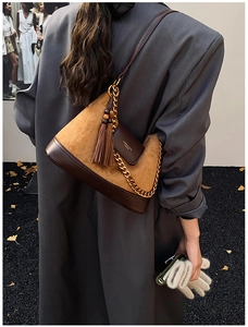 Detail of retro brown suede bag featuring gold chain strap and elegant tassel accessory