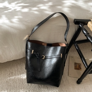 Détail du sac seau en cuir noir avec texture vintage et boucle dorée élégante