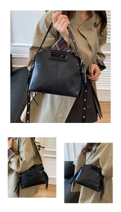 Détail du sac noir avec poignée évidée, œillets métalliques et pompons à franges