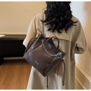 Dettaglio della borsa tote marrone con catena metallica e manico con stampa vintage