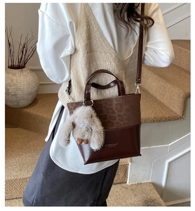 Detail of leopard print and brown leather bucket bag with a plush rabbit pendant