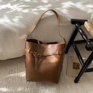 Gros plan d'un sac seau vintage en cuir marron avec sangle sur un tapis beige