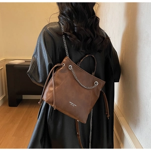 Dettaglio della borsa tote in pelle marrone scuro con catena d'argento e chiusura a coulisse