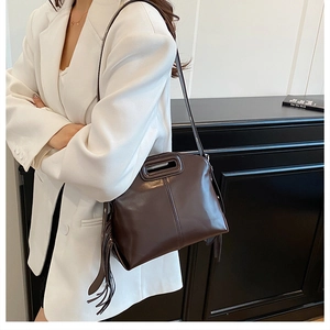 Détail du sac bandoulière en cuir marron foncé avec pompons vintage et surpiqûres