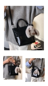 Detail of black leopard print bucket bag with grey rabbit plush pendant and crossbody strap