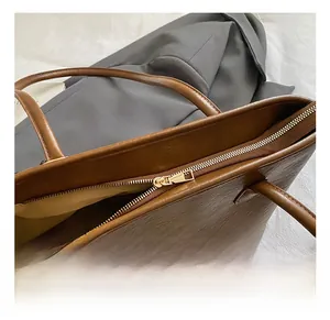 Détail de la fermeture éclair dorée et du cuir marron de haute qualité sur le sac cabas