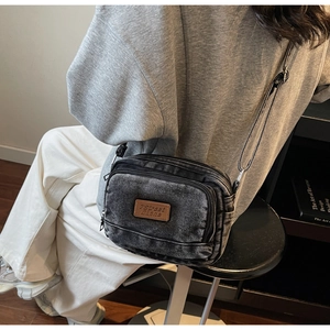 Détail du sac à bandoulière en denim délavé vintage avec compartiments zippés multiples