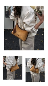 Detailed close-up of caramel suede crescent underarm bag with fringe and logo text