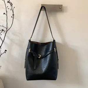 Détail d'un sac seau en cuir noir grainé avec boucle dorée et bandoulière réglable