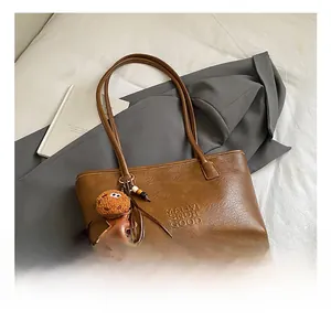 Détail du sac cabas vintage en cuir marron avec charm bonhomme de pain d'épices et logo