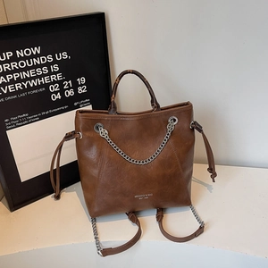 Dettaglio della borsa tote in pelle marrone con catena d'argento e scritte del logo