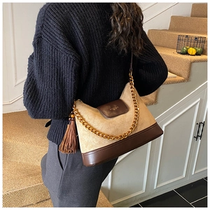 Close-up of retro beige suede shoulder bag with brown leather trim and gold chain detail
