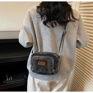 Vue détaillée du sac bandoulière en denim gris rétro avec sangle réglable et zips