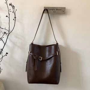 Détail du sac seau vintage marron foncé avec texture cuir et sangle à boucle métallique