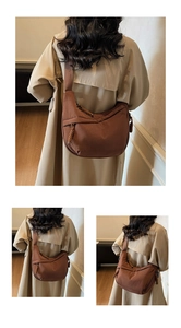 Detail view of brown canvas half-moon crossbody bag with wide strap and woven zipper pull