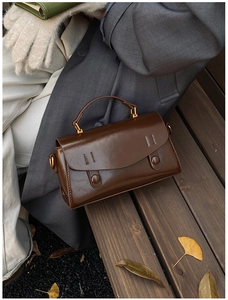 Borsa a mano vintage marrone su una panca di legno con sfondo di foglie autunnali