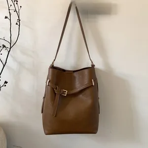 Détail du sac seau marron caramel avec texture cuir, sangle à boucle et finitions dorées
