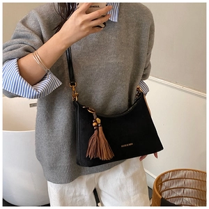 Detail of black suede underarm bag with brown beaded tassels and KOSK & MBR logo detail