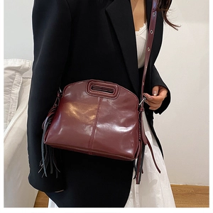 Détail d'un sac à main bordeaux avec franges et poignée découpée sur modèle