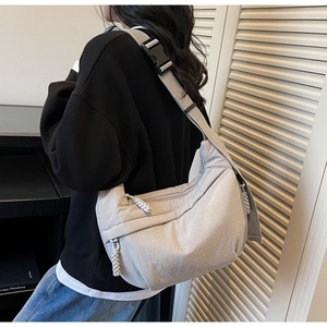 Detail of wide adjustable grey fabric strap and large black buckle on a canvas hobo bag