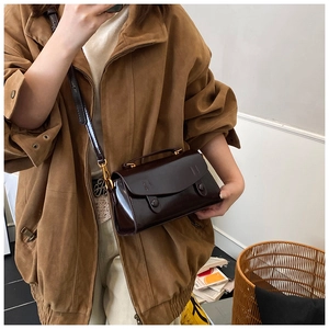 Dettaglio di una borsa vintage marrone scuro lucida con finiture dorate e manico superiore