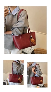 Détail du sac cabas en cuir rouge foncé avec texte embossé et breloque biscuit en peluche