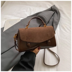 Dettaglio di una borsa quadrata marrone opaca con doppie texture e fibbie in metallo