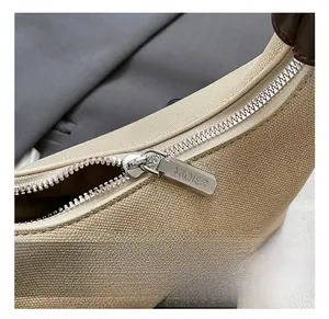Close-up of premium silver metal zipper hardware on beige canvas bucket handbag