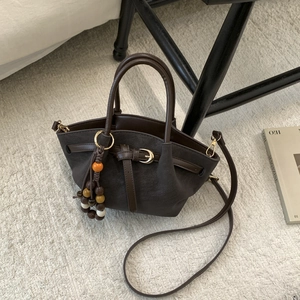 Vue détaillée du sac à main marron foncé avec charme perlé bohème et détails en métal doré chic