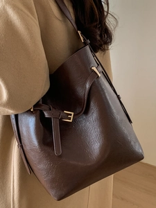 Sac seau minimaliste en cuir marron foncé avec détails dorés pour femme, vue de profil
